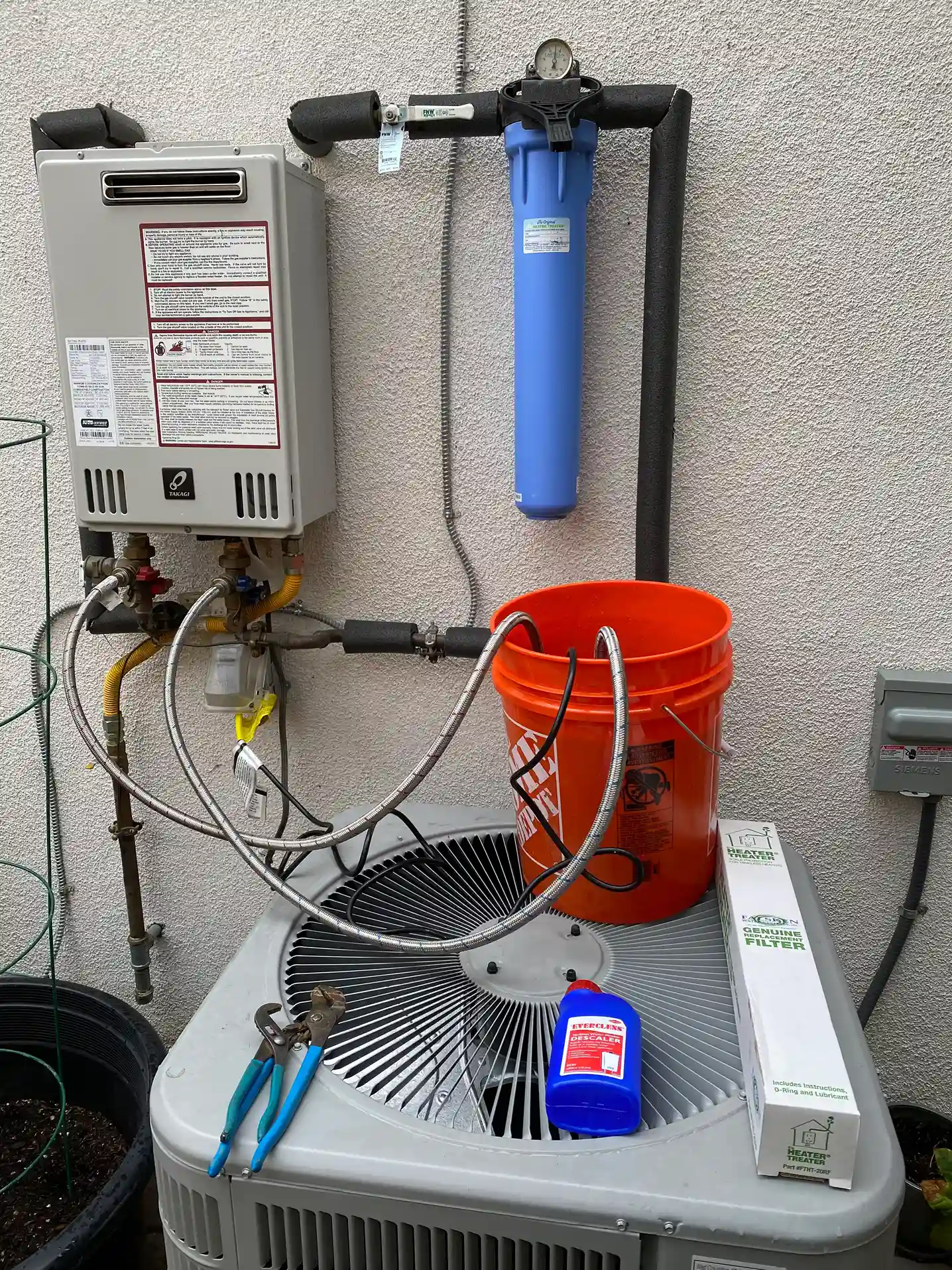 Plumber descaling a wall-mounted tankless water heater in a Calabasas home
